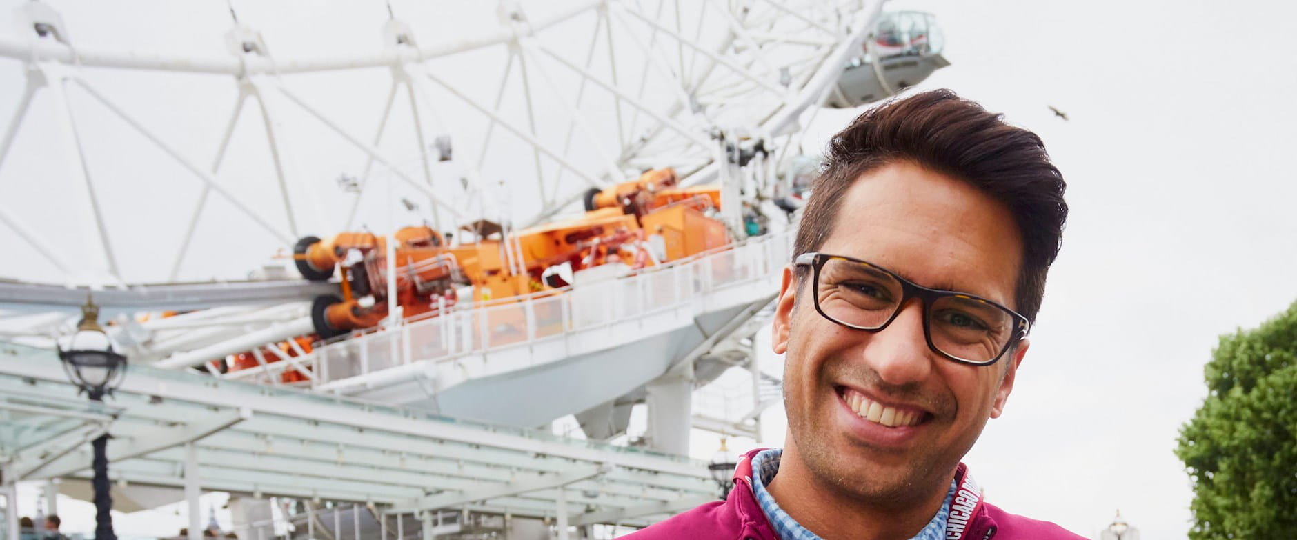 A Chicago Booth student smiles in front of the London Eye Ferris wheel
